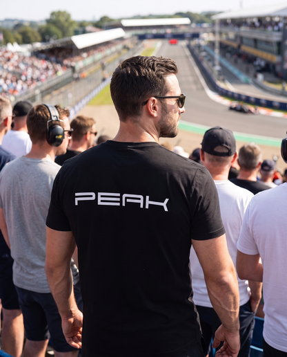 PEAK Tee wordmark back print worn in a grand prix grandstand
