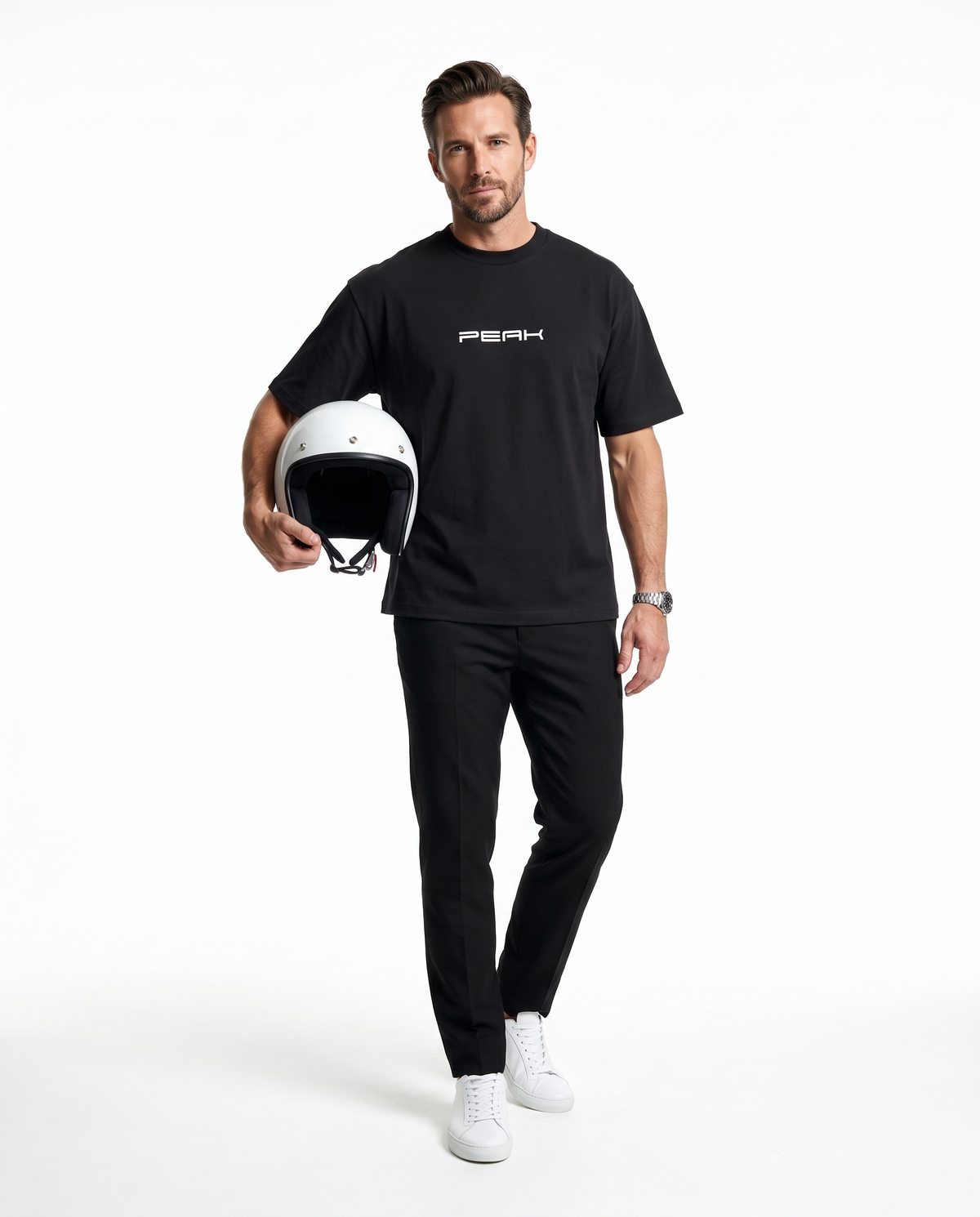 Man wearing the PEAK Heavy Tee in Black, holding a white racing helmet