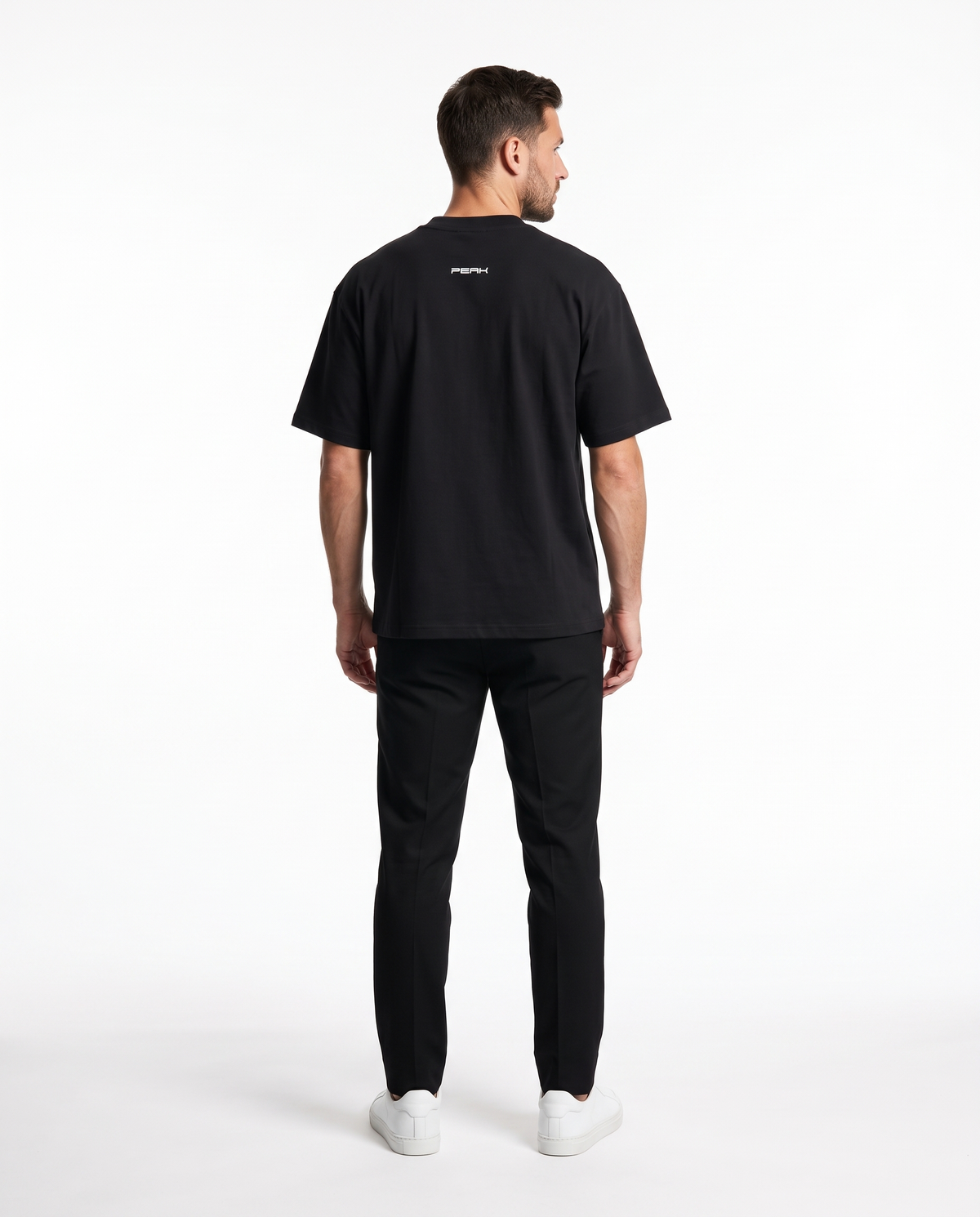 Back view of the PEAK Back Neck Tee in Black showing the small wordmark under the collar