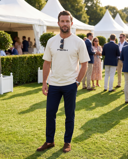 Man wearing the PEAK Heavy Tee in Ecru on the lawn at a grand prix hospitality garden